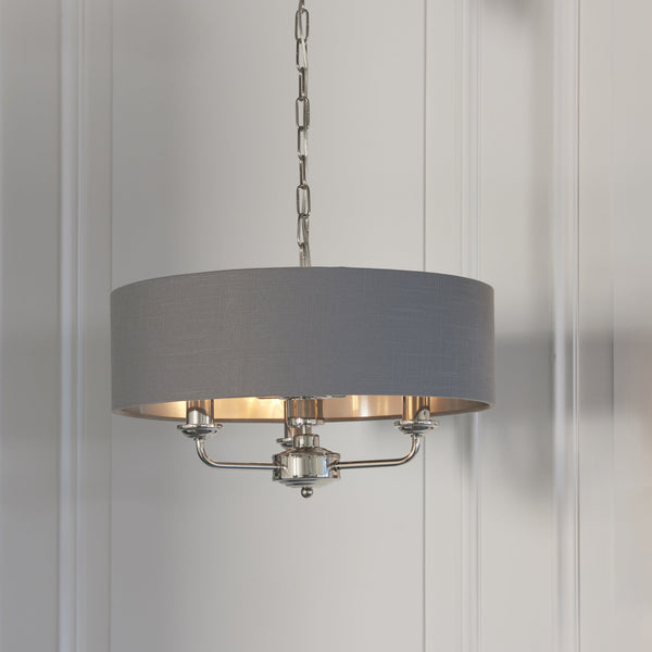 Endon Highclere 3-Light Pendant Drum Light Bright Nickel & Charcoal – A modern pendant light featuring a charcoal fabric shade, brushed metallic inner lining, and bright nickel metalwork. Height-adjustable and dimmable, this sophisticated statement piece is perfect for dining rooms, bedrooms, and contemporary interiors.