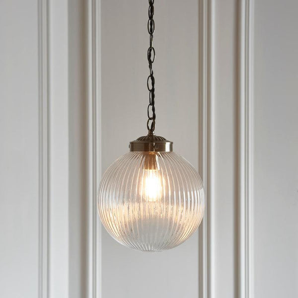 The Endon Brydon 1 Light Globe Pendant features clear ribbed glass with an antique brass finish, offering timeless elegance. Perfect for adding a sophisticated touch to your kitchen, hallway, or living room, this dimmable pendant light is compatible with filament LED bulbs for energy efficiency and beautiful lighting effects.
