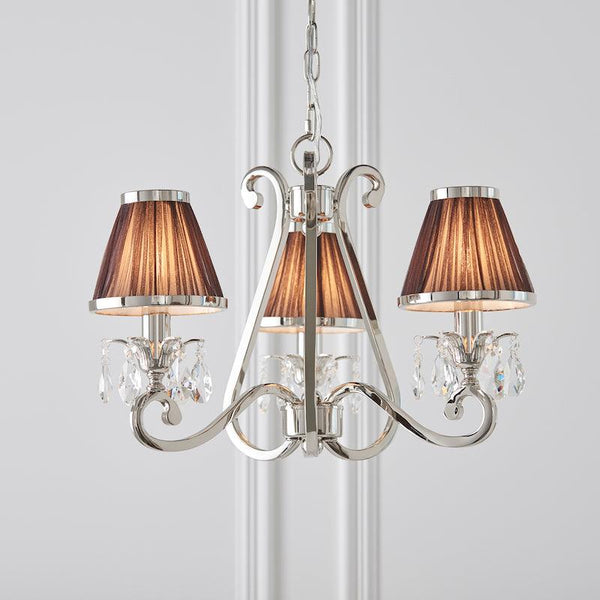 Interiors 1900 Oksana 3-Light Crystal Chandelier in Polished Nickel with Chocolate Shades – A luxurious chandelier featuring a sleek nickel finish, faceted crystal embellishments, and three arms adorned with rich chocolate fabric shades. Adjustable height (45cm-135cm), dimmable compatible, and uses 3 x E14 bulbs (not included).