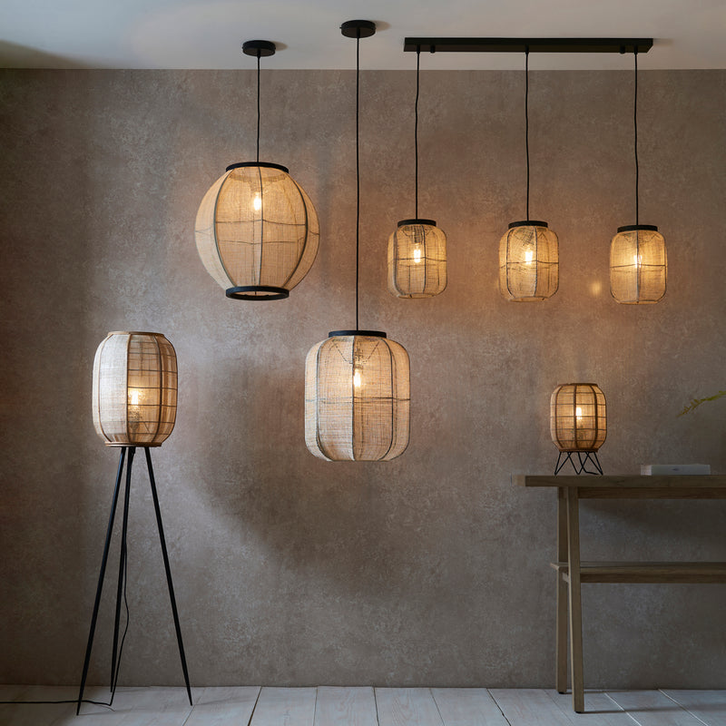 Zaire Tripod Floor Lamp lit up in a living room setting