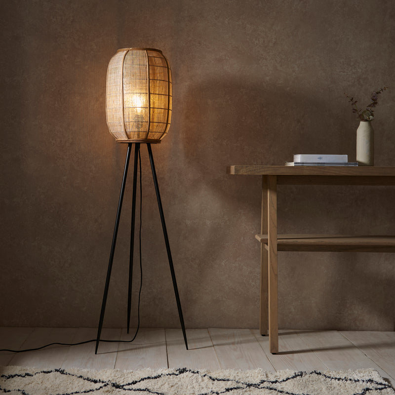 Zaire Tripod Floor Lamp lit up in a living room setting