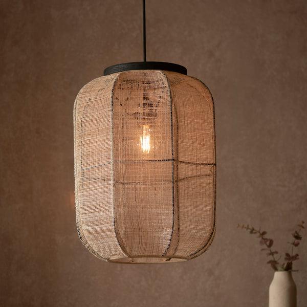 Zaire Medium Pendant in natural linen and dark plywood hanging in a living room
