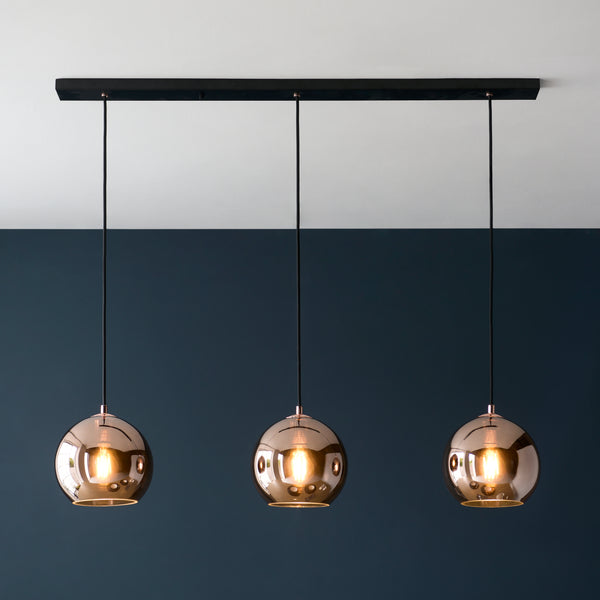 Boli 3 Light Linear Pendant in matt black and copper glass hanging in a kitchen