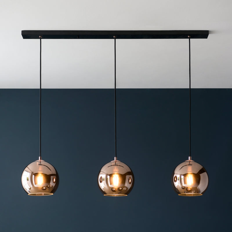 Boli 3 Light Linear Pendant in matt black and copper glass hanging in a kitchen