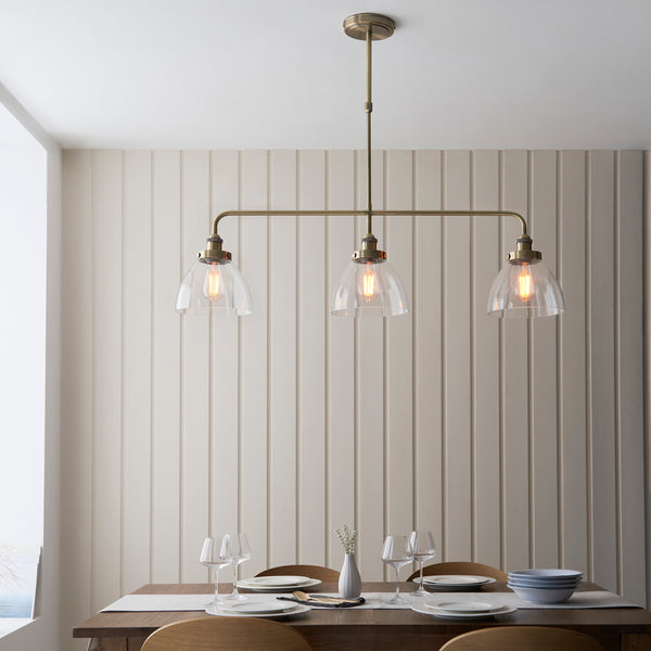 Hansen 3 Light Linear Bar Pendant in antique brass hanging in a kitchen