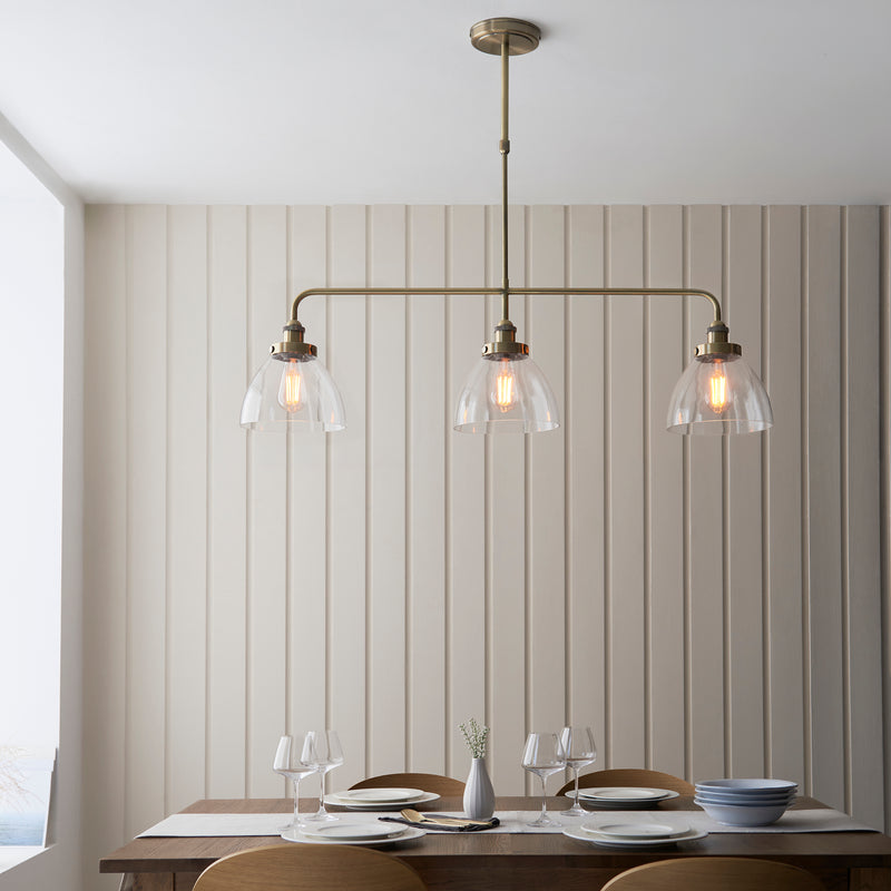 Hansen 3 Light Linear Bar Pendant in antique brass hanging in a kitchen