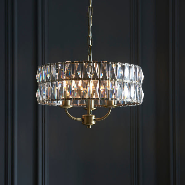Clifton 3 Light Pendant in antique brass hanging in a bedroom