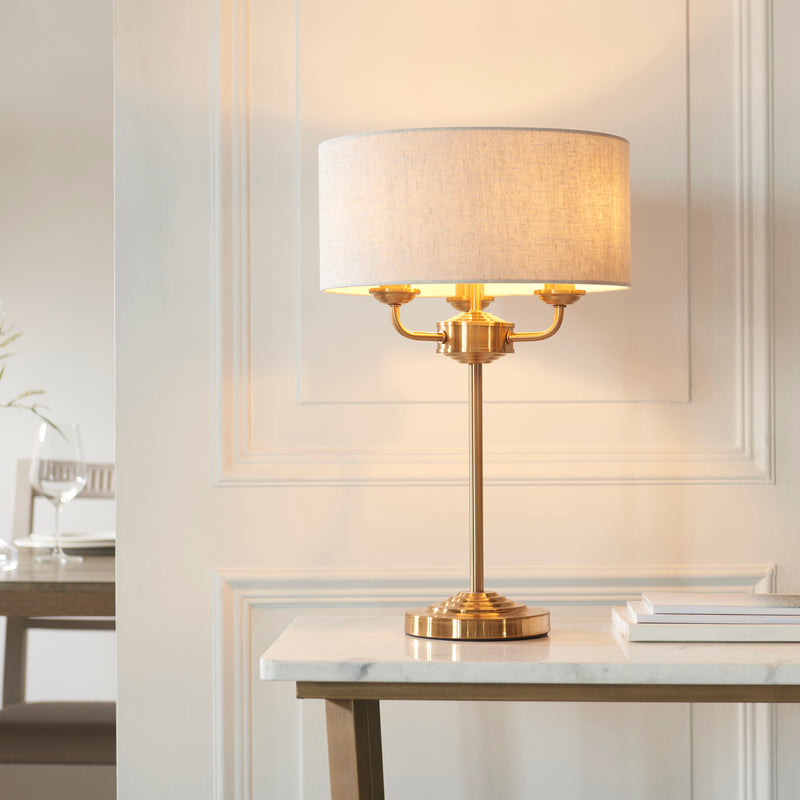 Endon Highclere 3 Light Table Lamp in vintage brass and linen in a styled living room