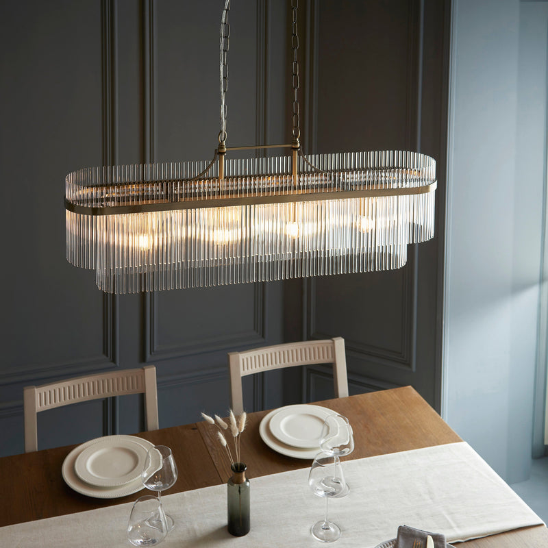 Endon Marietta 4-Light Linear Ceiling Pendant in Antique Brass & Glass features a decorative glass rod design, adjustable height chain, and a warm antique brass finish. Dimmable and LED-compatible, this elegant lighting fixture is perfect for dining rooms, kitchen islands, and stylish interiors.