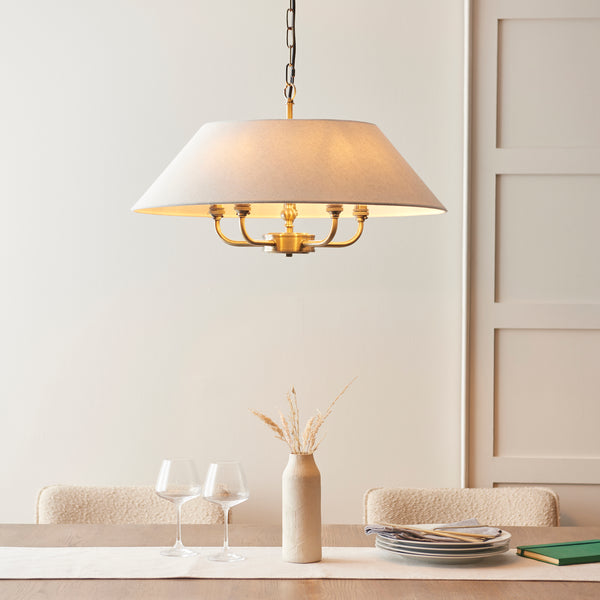 Lille 5 Light Pendant in antique brass and natural linen hanging in a living room
