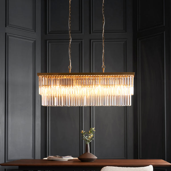 Conaston 4 Light Linear Chandelier in brushed aged brass hanging in a dining room