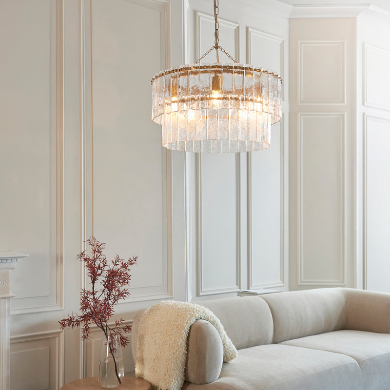 Karine 5 Light Tiered Pendant in brushed aged brass hanging in a living room