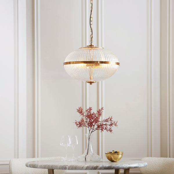 Somerset 3 Light Pendant in vintage brass hanging in a living room