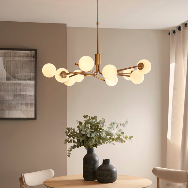 Aaron 10 Light Globe Pendant in brushed aged brass hanging in a living room