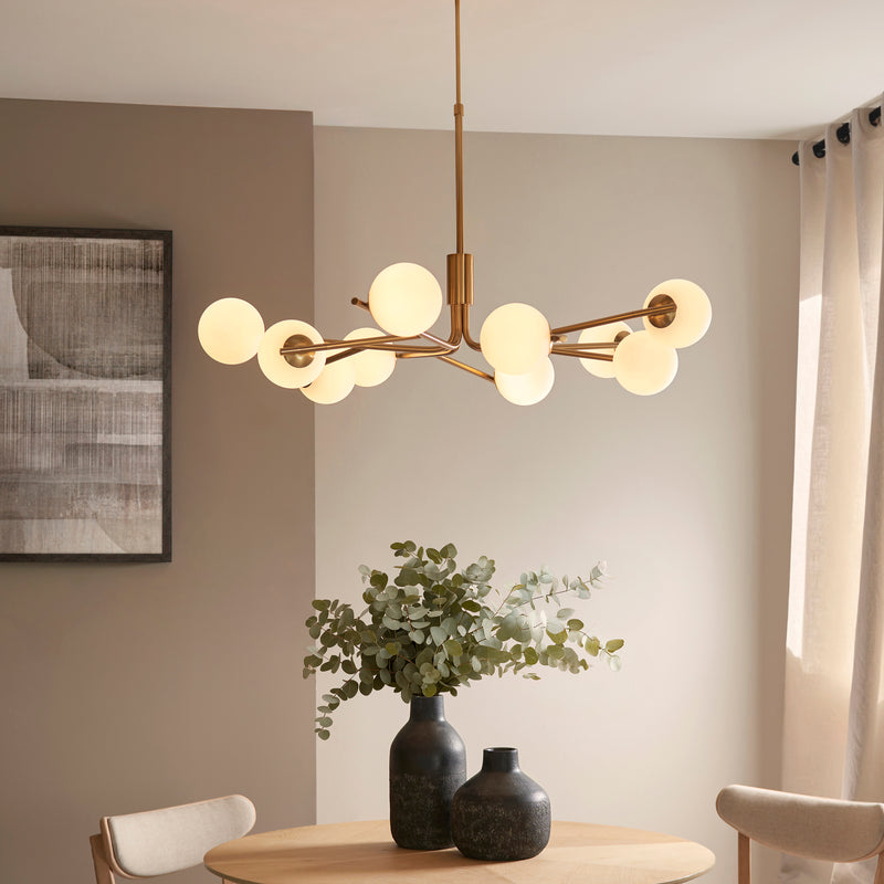 Aaron 10 Light Globe Pendant in brushed aged brass hanging in a living room