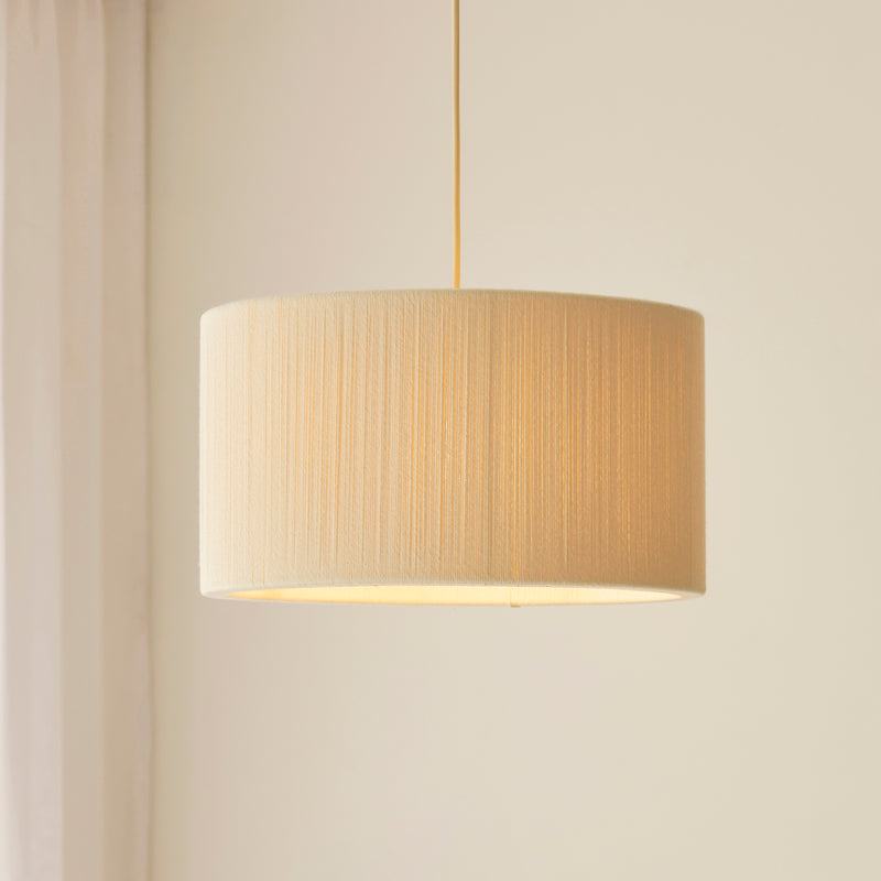 Noah Pendant in brushed brass and cream cotton shown in a room setting
