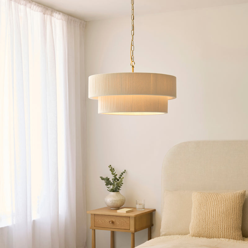 Noah 5 Light Tiered Pendant in brushed brass and cream cotton hanging in a living room