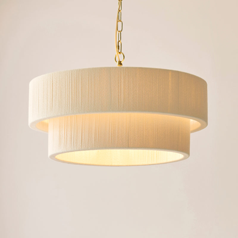 Noah 5 Light Tiered Pendant in brushed brass and cream cotton shown in a room setting