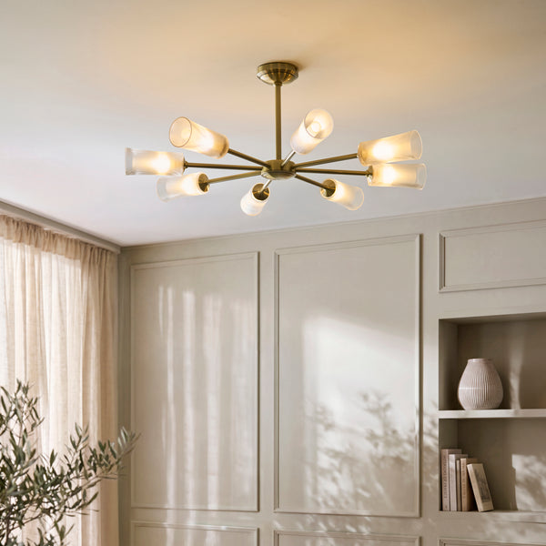 Avelyn 8 Light Chandelier in antique brass hanging in a living room