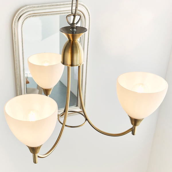 Alton 3 Light Pendant in antique brass hanging in a bedroom