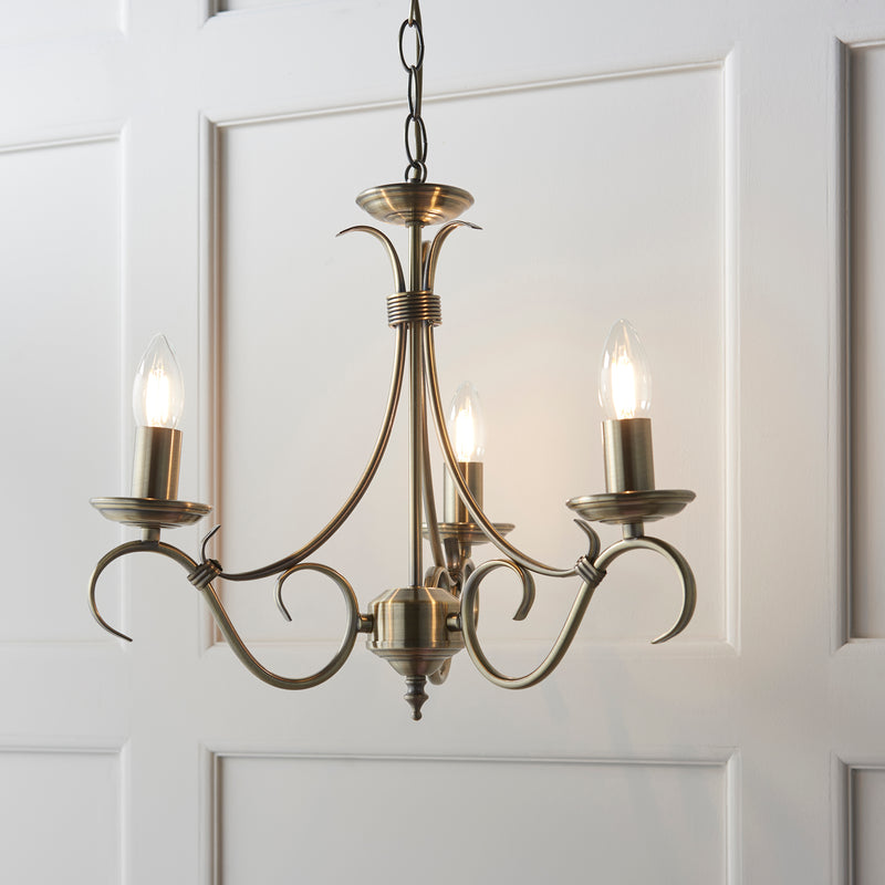Bernice 3 Light Chandelier in antique brass hanging in a bedroom