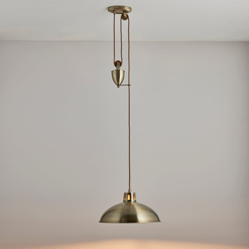 Polka Rise and Fall Pendant in antique brass hanging in a dining room
