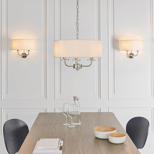 Nixon 3 Light Chandelier in bright nickel hanging in a bedroom