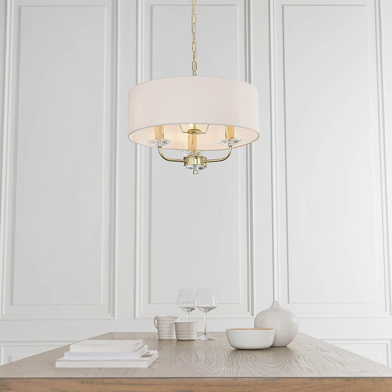 Nixon 3 Light Chandelier in brass hanging in a bedroom