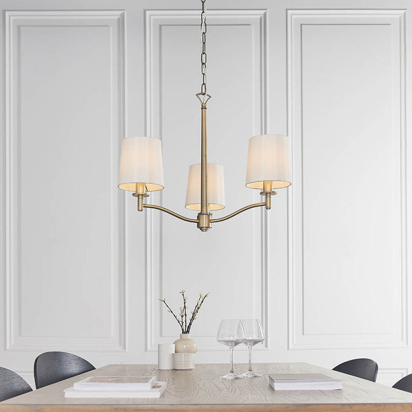 Ortona 3 Light Chandelier in matt antique brass hanging in a bedroom