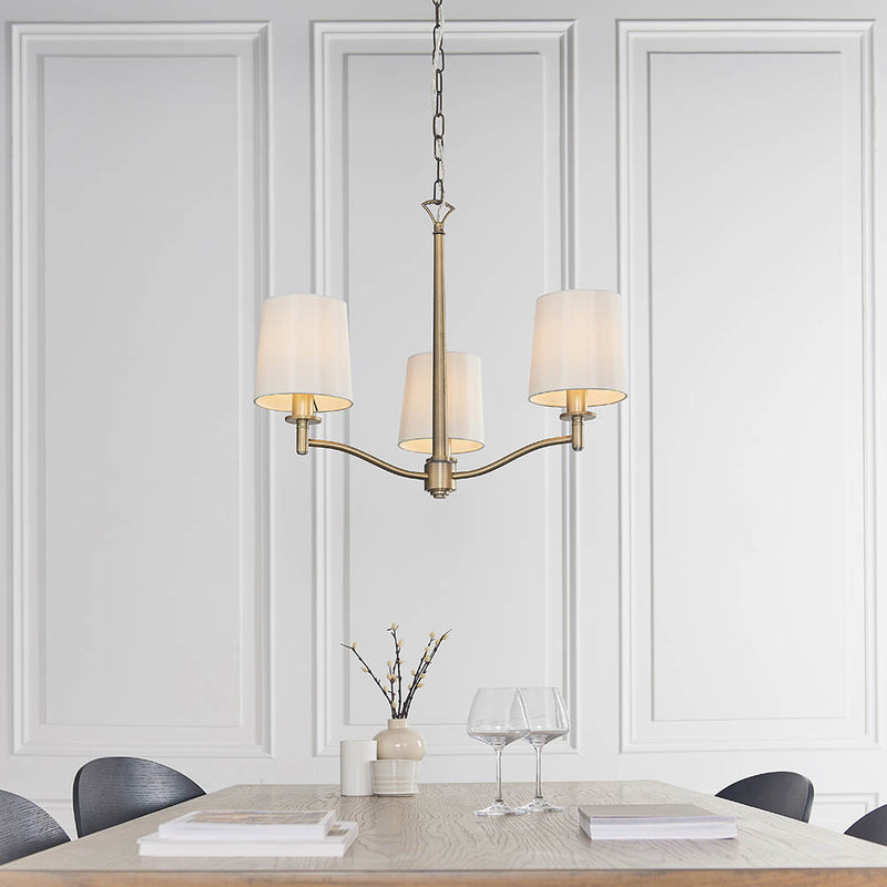 Ortona 3 Light Chandelier in matt antique brass hanging in a bedroom
