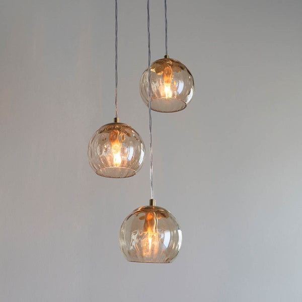 Dimple 3 Light Pendant lit up in a styled dining room