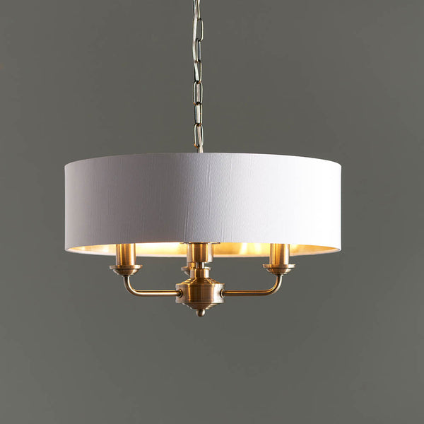 Highclere 3 Light Drum Pendant in antique brass hanging in a bedroom