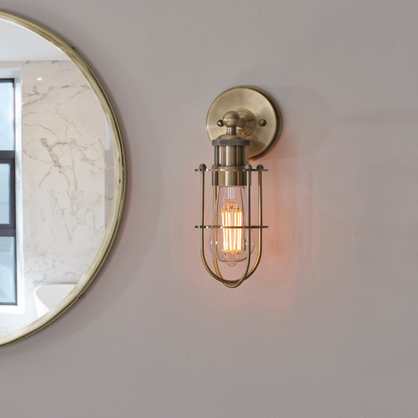 Crew Bathroom Wall Light in antique brass shown in a room setting