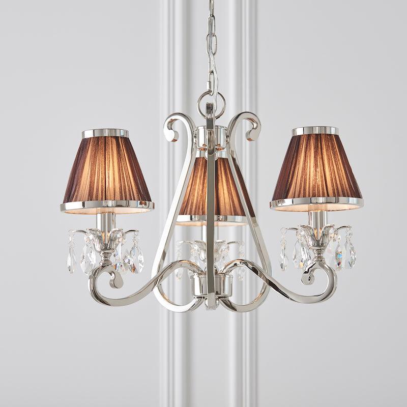 Interiors 1900 Oksana 3-Light Crystal Chandelier in Polished Nickel with Chocolate Shades – A luxurious chandelier featuring a sleek nickel finish, faceted crystal embellishments, and three arms adorned with rich chocolate fabric shades. Adjustable height (45cm-135cm), dimmable compatible, and uses 3 x E14 bulbs (not included).