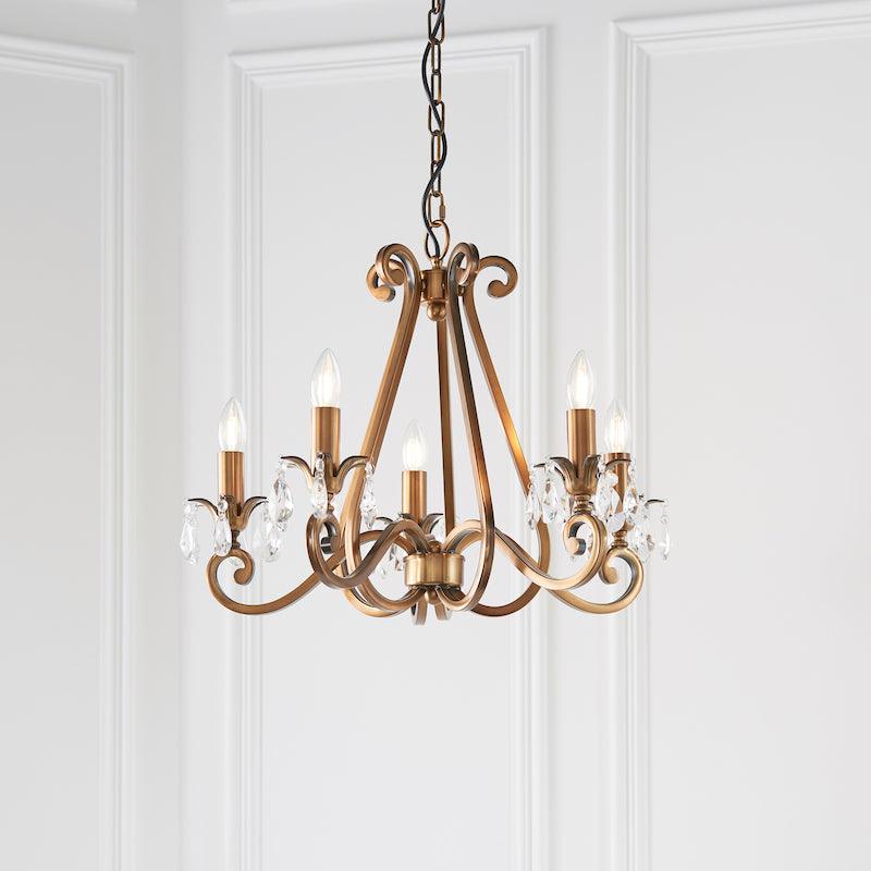 Interiors 1900 Oksana 5-Light Crystal Chandelier in Antique Brass – A classic chandelier featuring an antique brass finish, faceted crystal details, and five elegantly curved arms. Adjustable height (59cm-149cm), dimmable compatible, and uses 5 x E14 bulbs (not included).