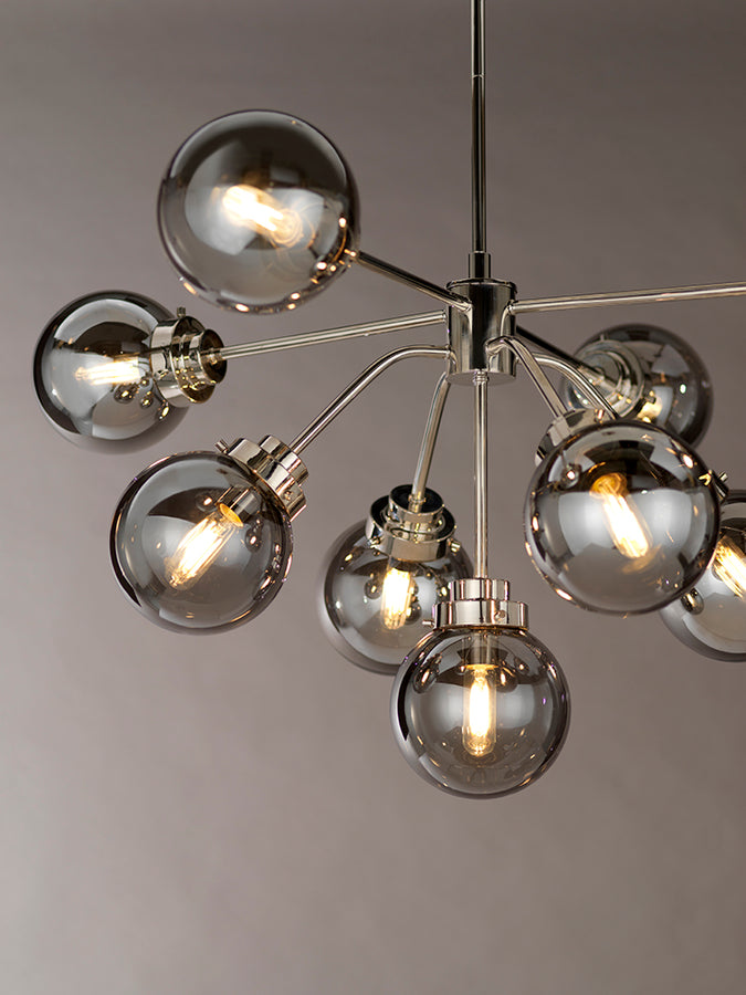 This Elstead Kula polished nickel 9 light chandelier with mirror globe shades is contemporary and stylish. Large ceiling light with circular mount, sectional rod suspension, and 88cm diameter body. Nine polished nickel arms lead to Deco-style smoked mirrored globe shades that become semi-transparent when lit. Modern luxury for your home.
